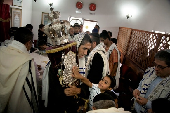 Many members of the Jewish community in Bello, Colombia, were raised as Christians. They believe their ancestors were Jews who fled the Spanish Inquisition, and so they are now Orthodox Jews. Here, a boy reaches out to the 120-year-old Torah that was written in Amsterdam and acquired by the community five years ago.