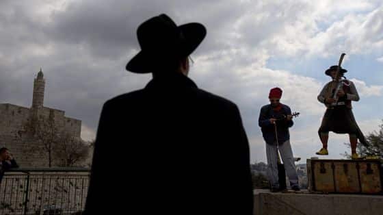 Un judío ultraortodoxo observa una actuación musical callejera frente a la Torre de David en el casco antiguo de Jerusalén. / SEBASTIAN SCHEINER (AP)