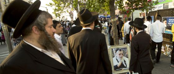 Judíos ultraortodoxos caminan junto a un retrato del difunto líder espiritual sefardí, Ovadia Yosef, el pasado octubre en Jerusalén. / SEBASTIAN SCHEINER (AP)