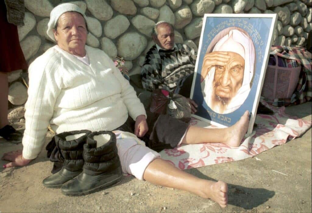 Judíos israelíes de ascendencia marroquí vistos en la tumba de Baba Sali en Netivot, Israel, mostrando un retrato del difunto rabino venerado, en 1990( Foto: Cortesía de Adil Faouzi )