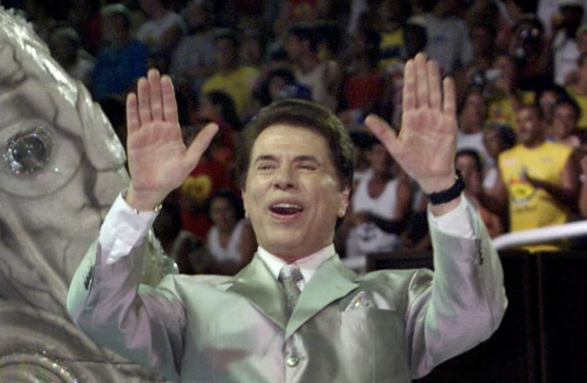 La personalidad televisiva más famosa de Brasil y presentador de varios programas de juegos, Silvio Santos, saluda a la multitud desde lo alto de su carroza para la escuela de samba 'Tradicao' durante un desfile nocturno en el estadio Sambódromo de Río de Janeiro el 25 de febrero de 2001.